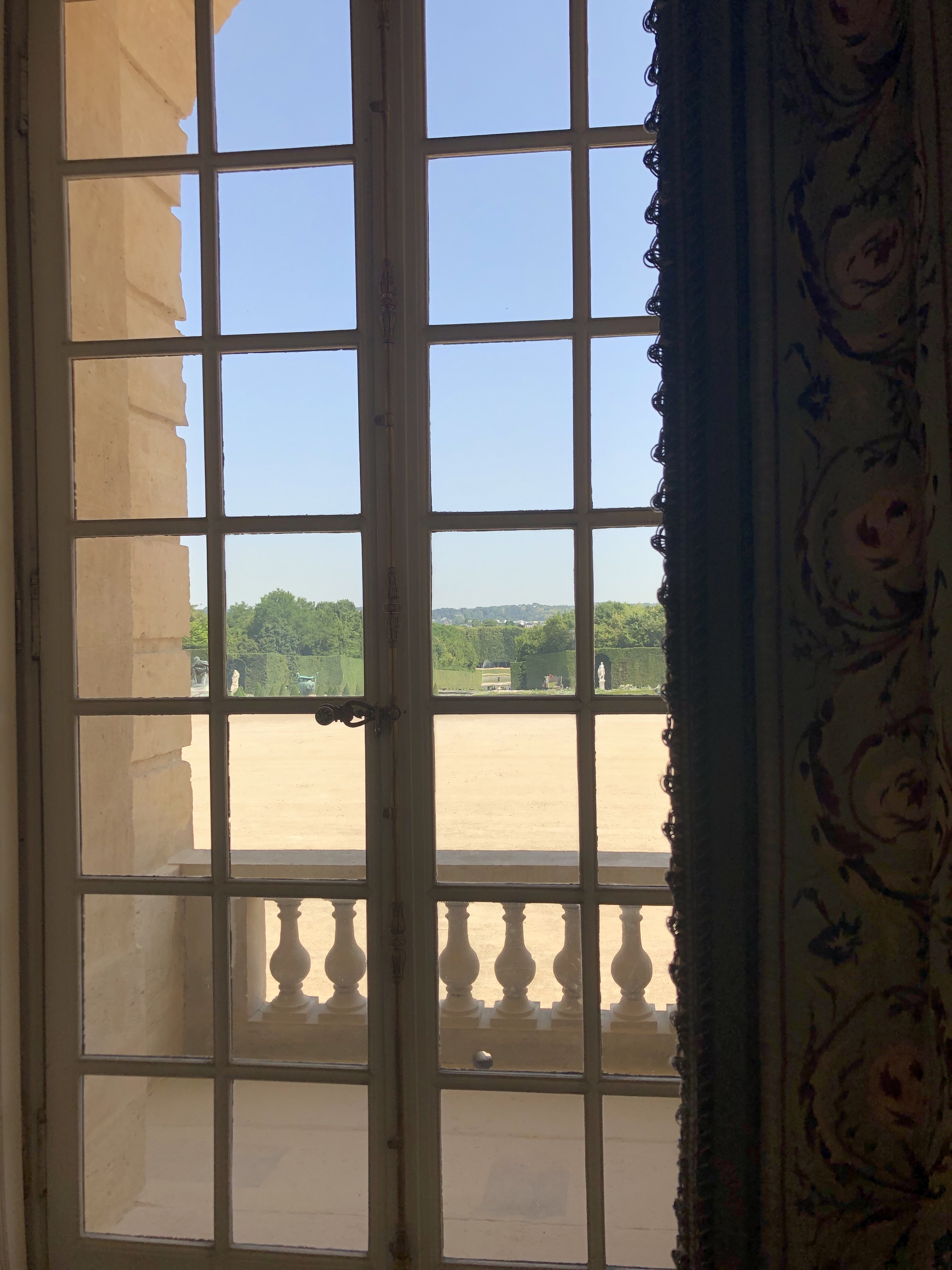 View through a window of sunny grounds at the palace of versailles